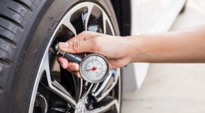 Close-up of a person checking tire pressure with a tire gauge, ensuring the tire is properly inflated for safe driving.