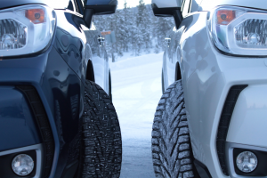 Two cars fitted with winter tires parked side by side on a snowy road, with visible tread patterns designed for snowy conditions