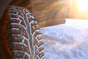 Close-up of a snow-covered winter tire, showing deep tread patterns designed for traction on icy and snowy roads.