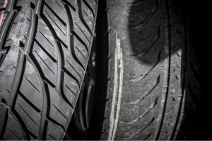 Comparison of a new tire with deep, intact tread next to a worn-out tire showing significant tread wear, illustrating the impact of regular use and the importance of proper tire maintenance for safety and longevity