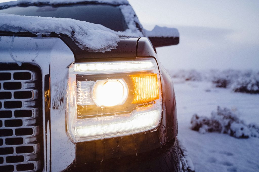 Close-up of a truck’s headlight covered with snow and ice on a winter day.